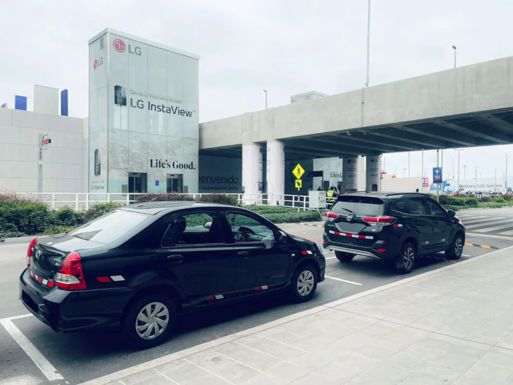Auto negro de Taxi Van Lima estacionado frente al Aeropuerto Jorge Chávez, ideal para traslados individuales o ejecutivos hacia Miraflores y San Isidro.